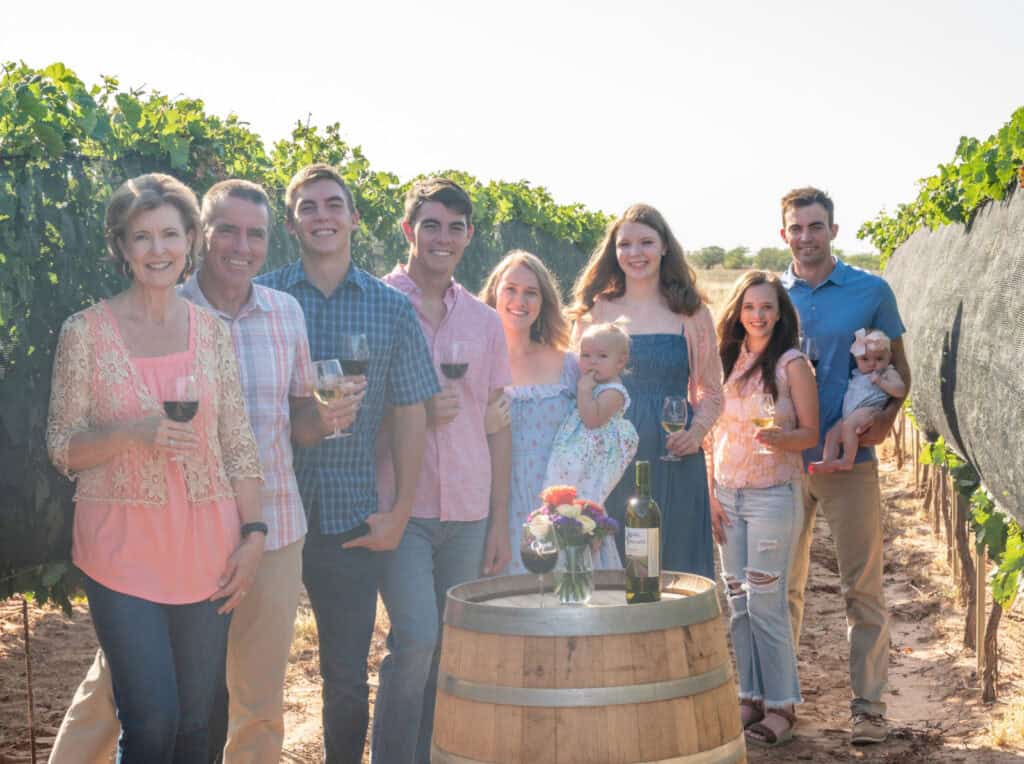 Oswald Vineyard family in vineyard around wine barrel.